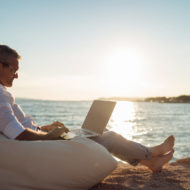 Man working on laptop at beach